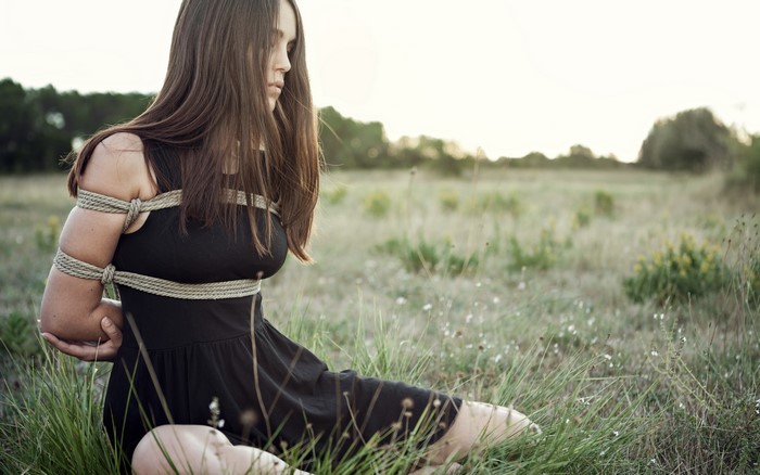 Woman tied with ropes in a field