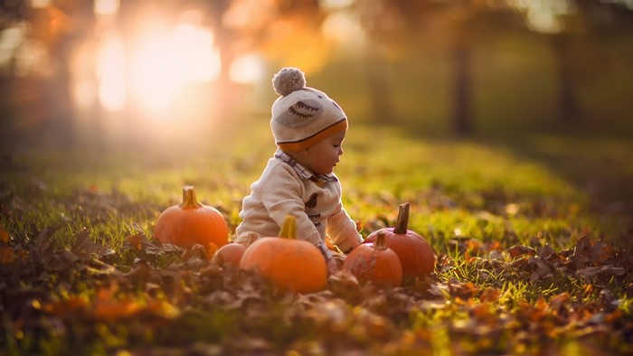 Baby in a pumpkin patch during autumn