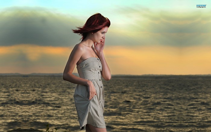 Woman in strapless dress by the sea at sunset