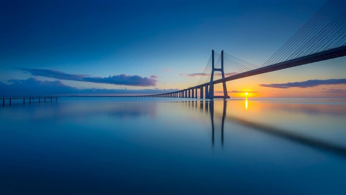 Vasco da Gama Bridge over calm water at sunset