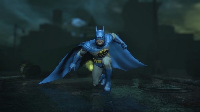 Batman in a blue and gray suit crouches on a wet street