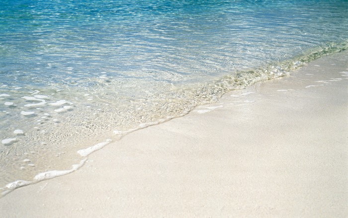 Clear ocean water washing onto a sandy beach