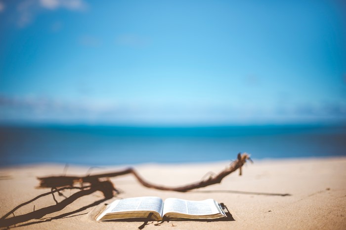 Open book on a sandy beach with driftwood