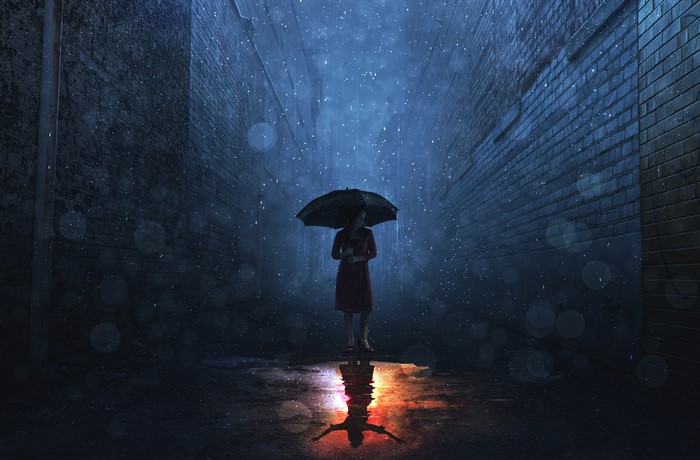 Woman in red dress holding umbrella in rainy alley