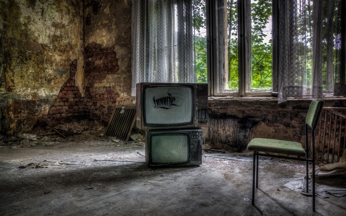 Abandoned room with old TVs and chair