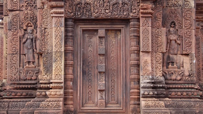 Intricately carved stone temple door with statues in Cambodia