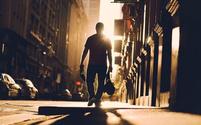Man walking down a sunlit city street