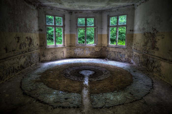 Abandoned room with circular floor pattern and windows