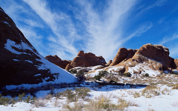 Snowy desert landscape with red rock formations and blue sky