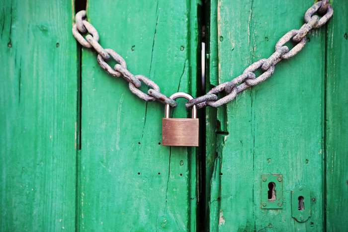 Green wooden door locked with a chain and padlock