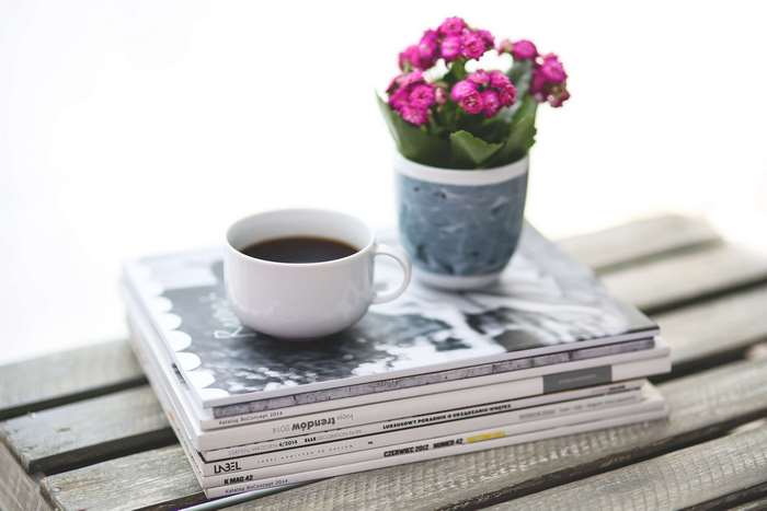 Coffee cup and pink flowers on magazines