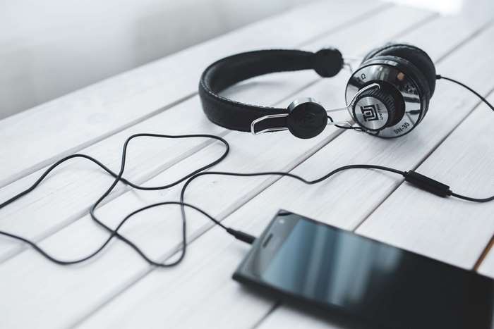 Headphones connected to a smartphone on a wooden table