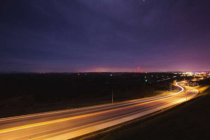 Highway at night with light trails and city lights