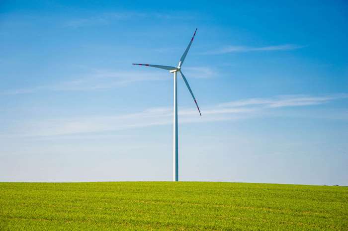 Wind turbine in a green field under a blue sky