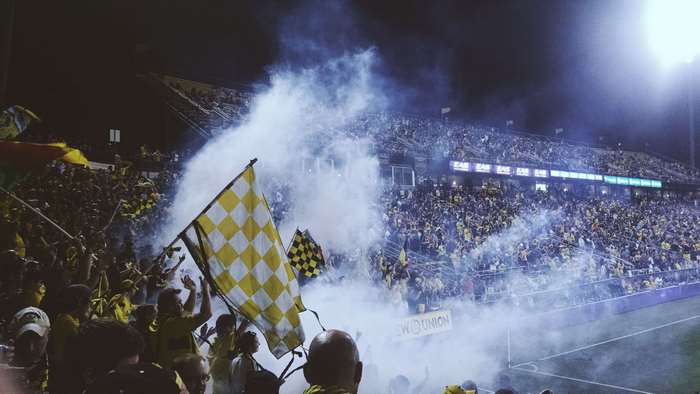 Soccer fans cheering with flags and smoke