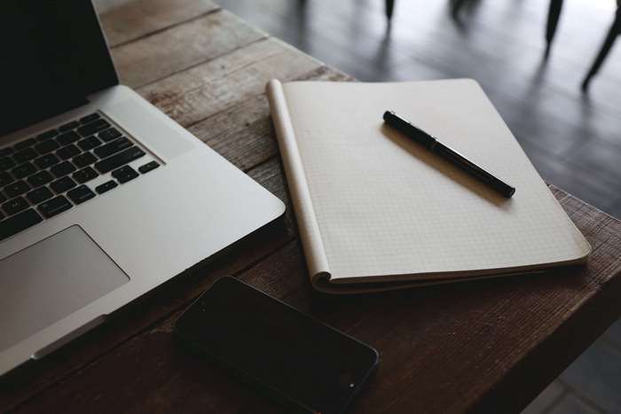 Laptop, notebook, pen, and smartphone on a wooden table