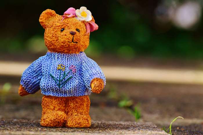 Orange teddy bear figurine with blue knitted sweater