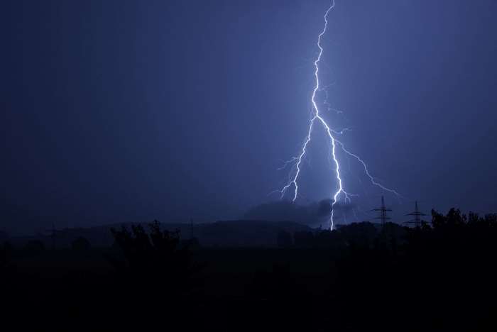 Lightning strike over dark landscape at night