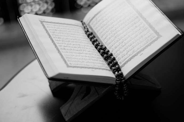 Quran on a wooden stand with prayer beads