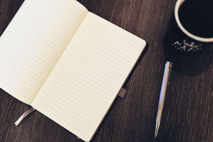 Open notebook with pen and coffee 4K
