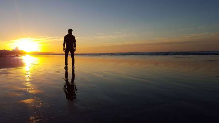 Man silhouetted on a beach at sunset