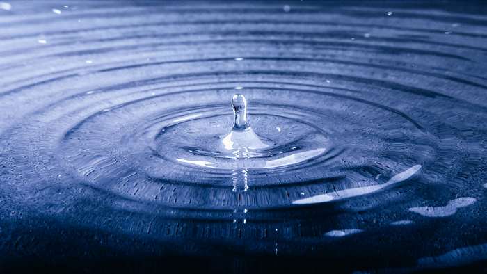 Blue water drop creating ripples