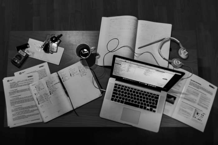 Overhead view of a desk with laptop, notebooks, and coffee