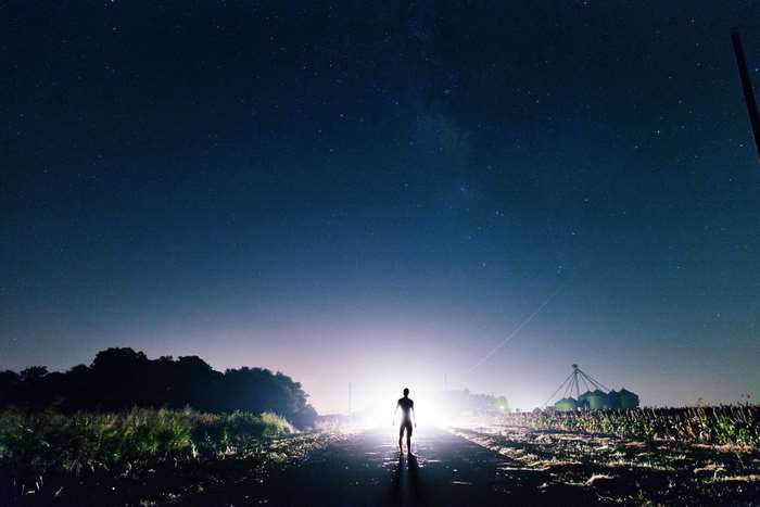 Man standing on road at night under stars