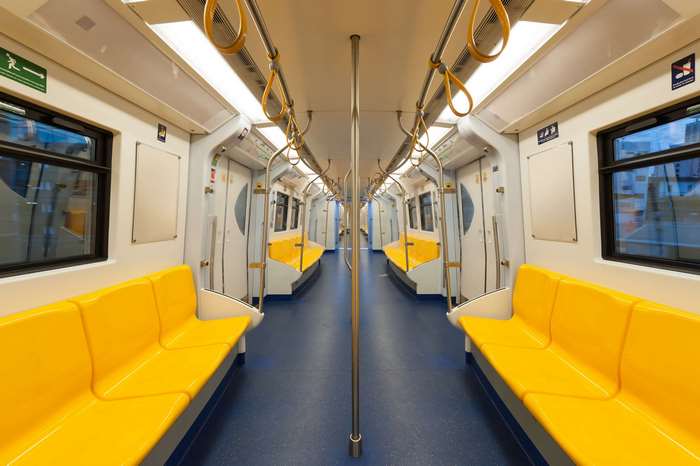 Interior of a modern, empty subway train with yellow seats