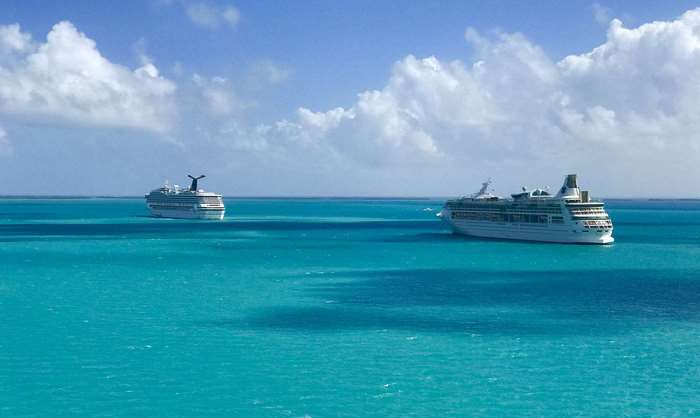 Two cruise ships in turquoise ocean under cloudy sky