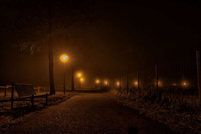 Night path with street lamps and fence