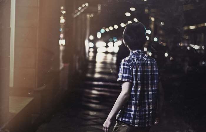 Boy in plaid shirt on a city street at night