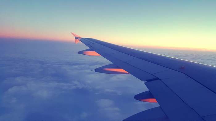 Airplane wing over clouds at sunset