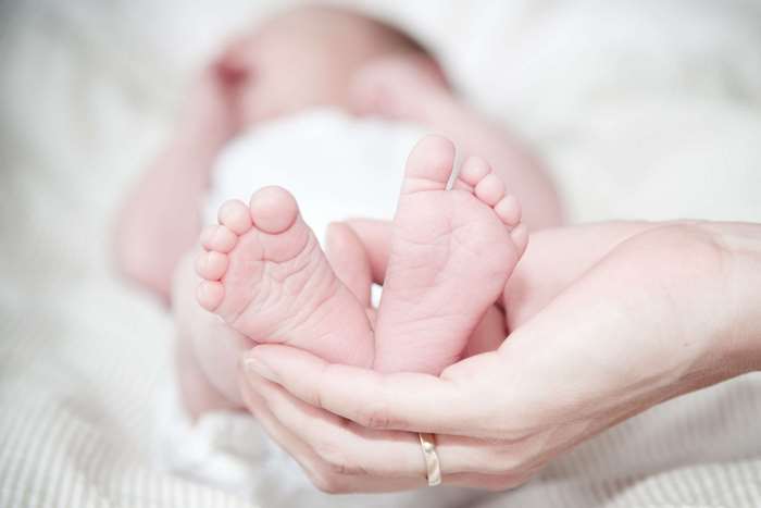 Newborn baby feet held in hands