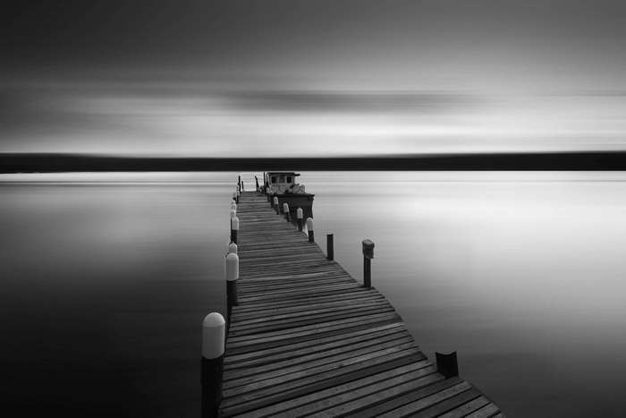 Black and white long exposure of a wooden pier and boat