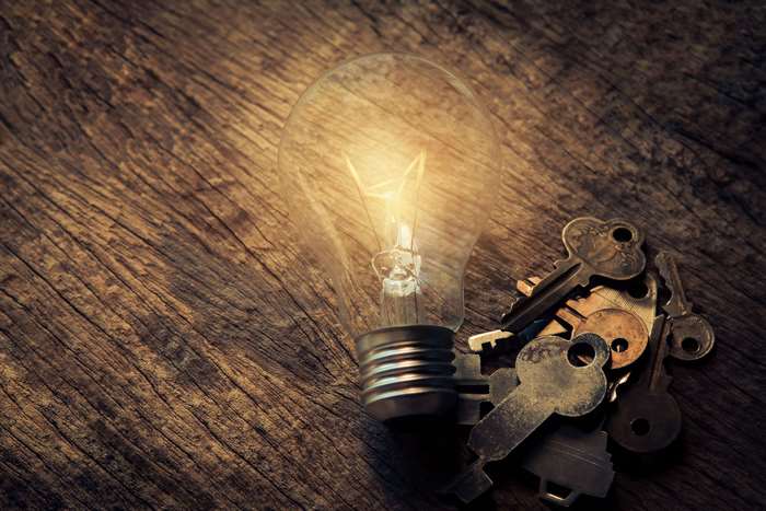 Light bulb and keys on a wooden surface