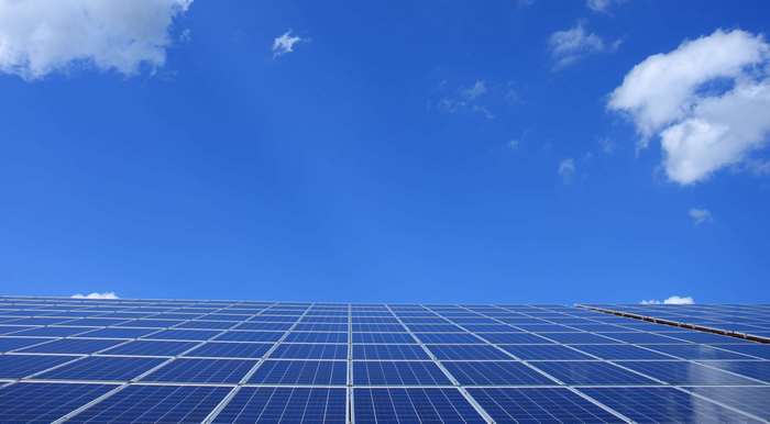 Solar panels under a blue sky with clouds
