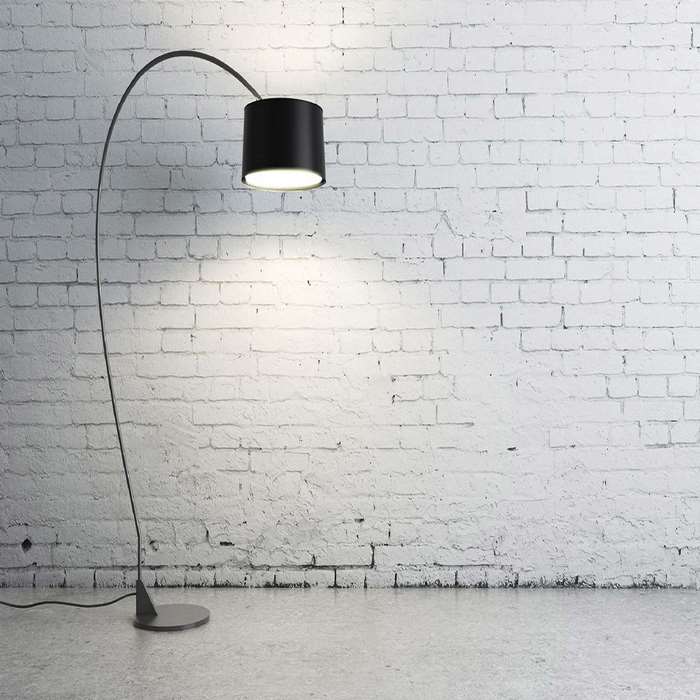 Black arc floor lamp against a white brick wall