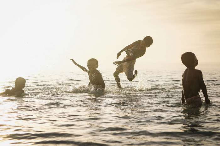 Children playing in the ocean at sunset 4K