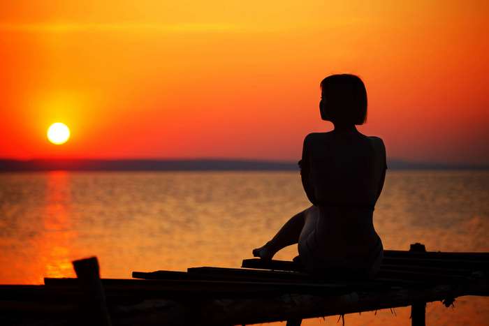 Woman silhouetted on a pier at sunset