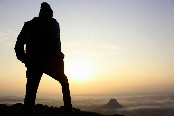 Man silhouetted on mountain top at sunrise