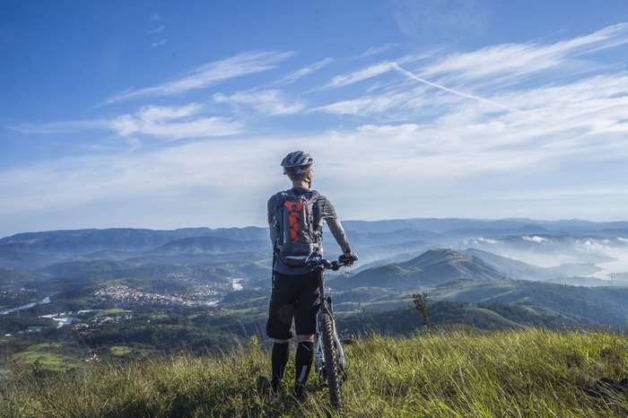 Cyclist on a grassy hilltop overlooking a valley