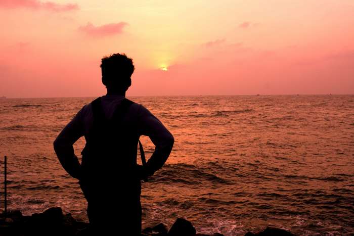 Silhouette of a man watching the sunset over the ocean
