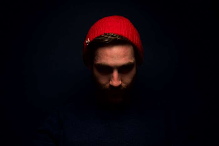 Man wearing a red beanie in dark studio portrait