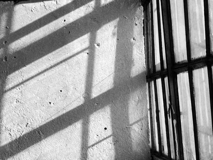 Shadows on a textured wall near a barred window