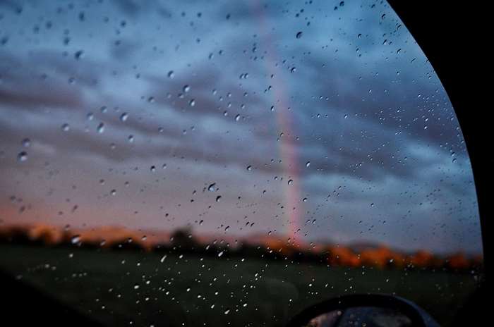 Rainy car window with rainbow and clouds 4K