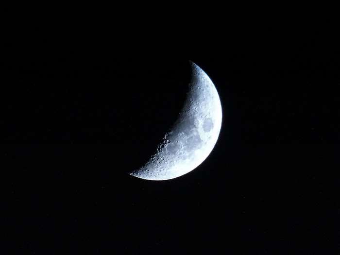 Crescent moon with craters in dark space