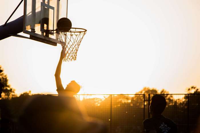 Silhouette of a person playing basketball at sunset