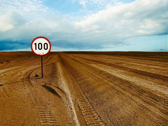 Speed limit sign 100 on a dirt road in a desert