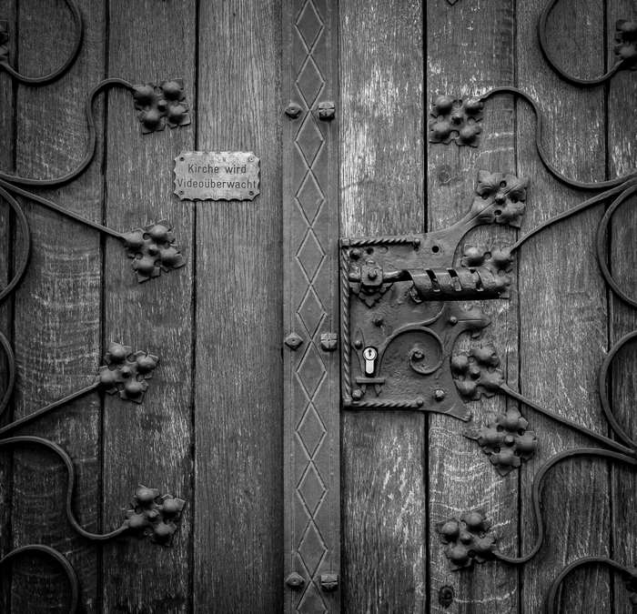 Close-up of a wooden door with ornate metalwork and a sign